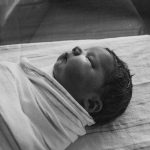 grayscale photography of sleeping baby covered by textile