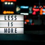 Less Is More signboard across blurry city lights